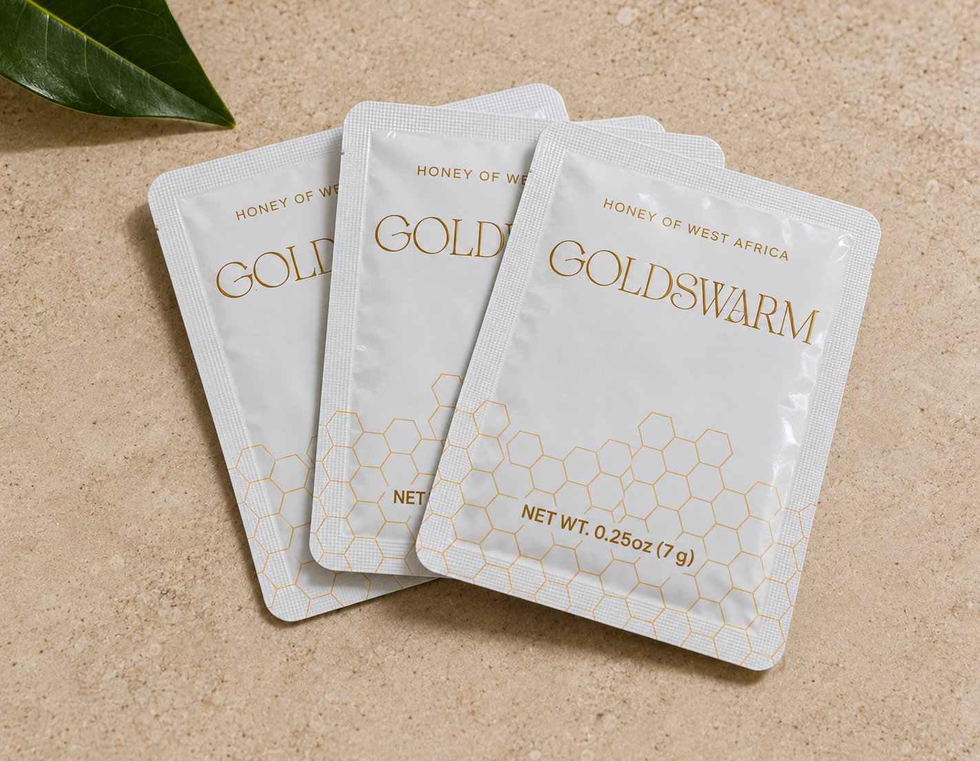 Three Goldswarm raw honey single-serve squeeze packets, 0.25 oz (7 g) each, on a stone surface